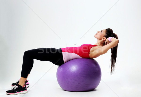 Young sport woman doing abs workout on fitball over gray background Stock photo © deandrobot