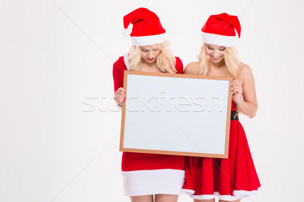 Sisters twins in santa dresses and hats holding blank board  Stock photo © deandrobot