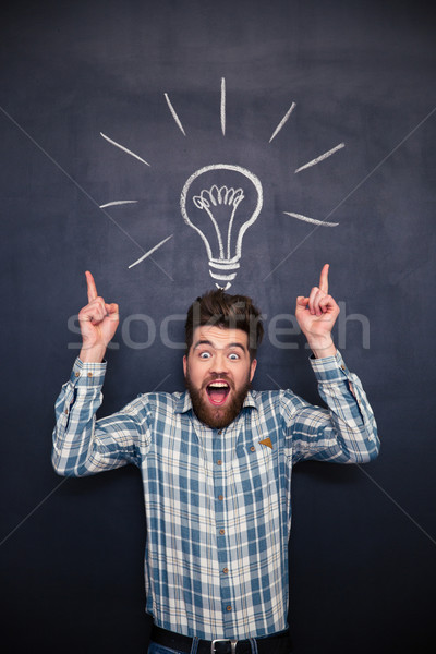 Funny man with tousled hair having idea over blackboard background Stock photo © deandrobot
