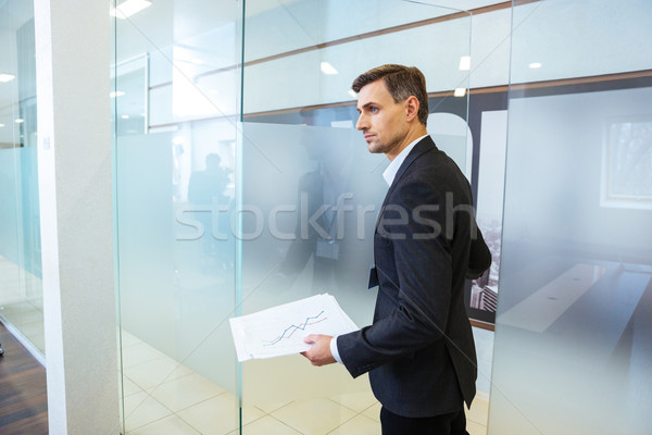 Confident businessman holding documents and entering the office Stock photo © deandrobot