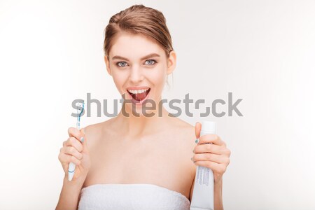 Joyful charming young woman holding toothpaste and toothbrush Stock photo © deandrobot