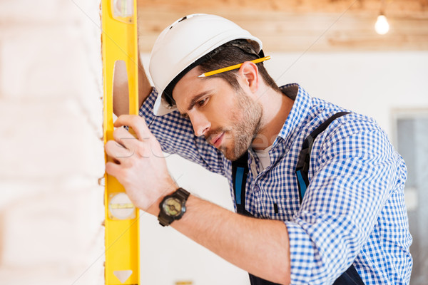 Close-up portrait of a handsome pensive builder holding level Stock photo © deandrobot