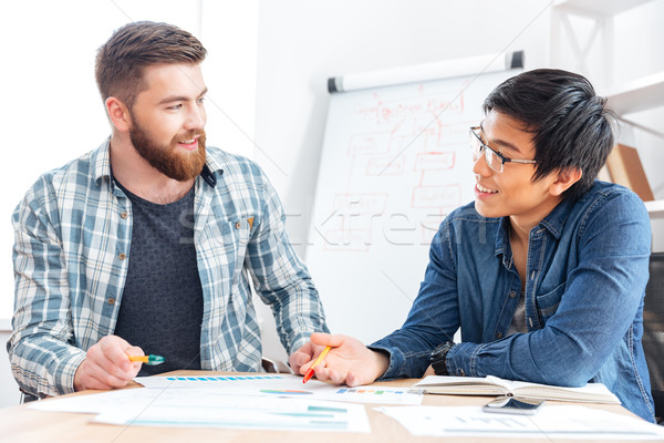 Two happy young businessmen working together in office Stock photo © deandrobot