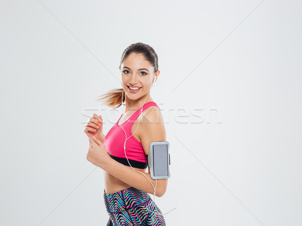 Smiling sports woman listening music in earphones Stock photo © deandrobot