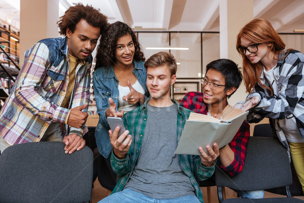 Homem leitura telefone móvel amigos em pé em torno de Foto stock © deandrobot