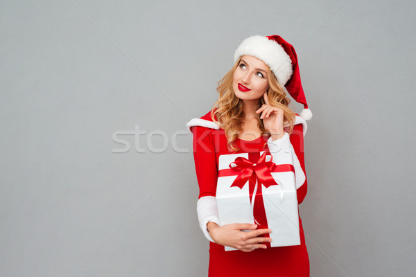 Wondered woman in red santa claus outfit holding christmas gift Stock photo © deandrobot