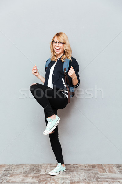 Cheerful young lady student make winner gesture. Stock photo © deandrobot