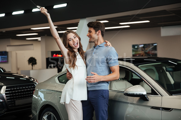 Lovng couple standing near car in car dealership. Stock photo © deandrobot