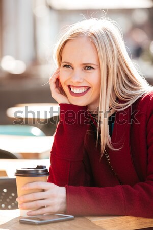 Smiling young caucasian woman sitting in cafe outdoors chatting. Stock photo © deandrobot