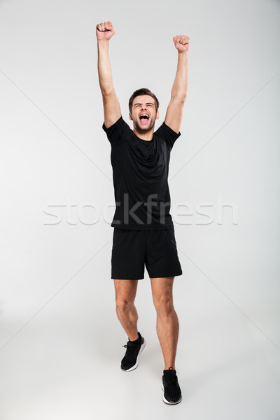 Full length portrait of a happy amused sportsman celebrating success Stock photo © deandrobot