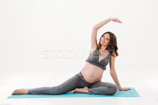 Happy pregnant woman doing fitness exercise on fitness mat Stock photo © deandrobot