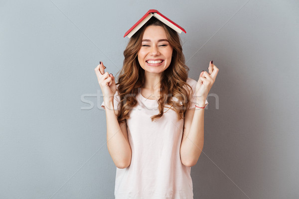 Portrait of a happy girl holding book on her head Stock photo © deandrobot