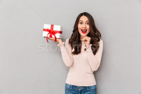 Adorable image of woman with red lips holding bithday present in Stock photo © deandrobot
