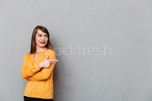 Portrait of a woman pointing finger away at copy space Stock photo © deandrobot