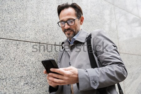 Portré mosolyog szakállas férfi sms chat mobiltelefon Stock fotó © deandrobot