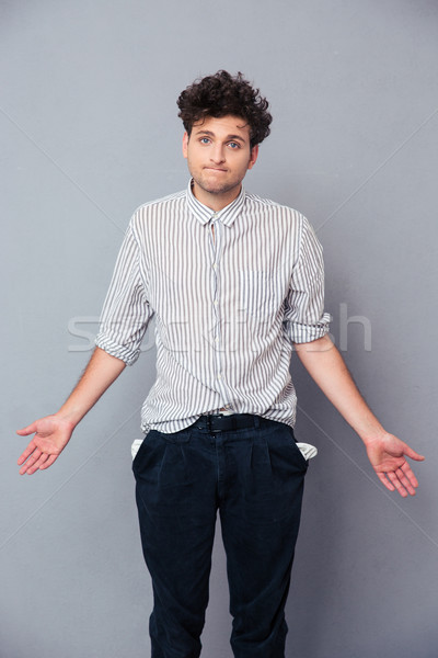 Man shrugging and showing his empty pocket Stock photo © deandrobot