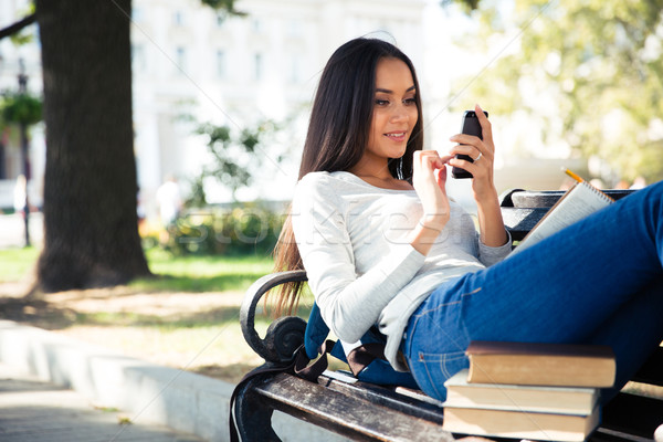 Female student lying on the bench and using smartphone Stock photo © deandrobot