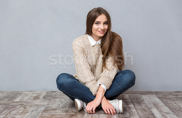 Belle souriant fille séance étage jambes croisées [[stock_photo]] © deandrobot