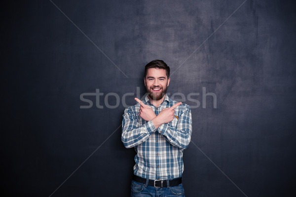 Smiling casual man pointing fingers away  Stock photo © deandrobot