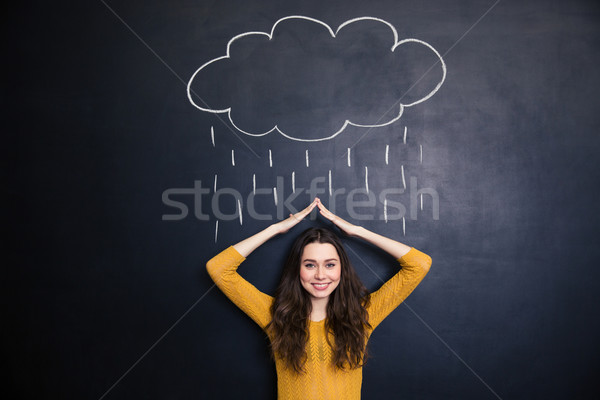 Cheerful woman covering from drawn rain with hands over chalkboard  Stock photo © deandrobot