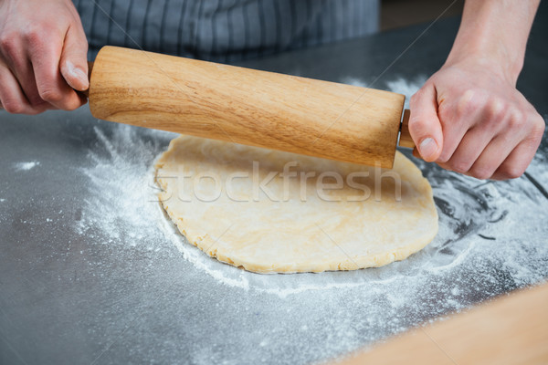 Hands of man rolling out dough on the table Stock photo © deandrobot