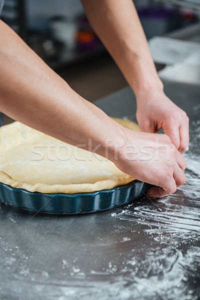 Male hands cooking pie in baking pan Stock photo © deandrobot