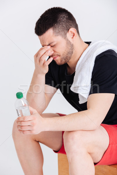 Stock photo: Tired sports man holding bottle with water