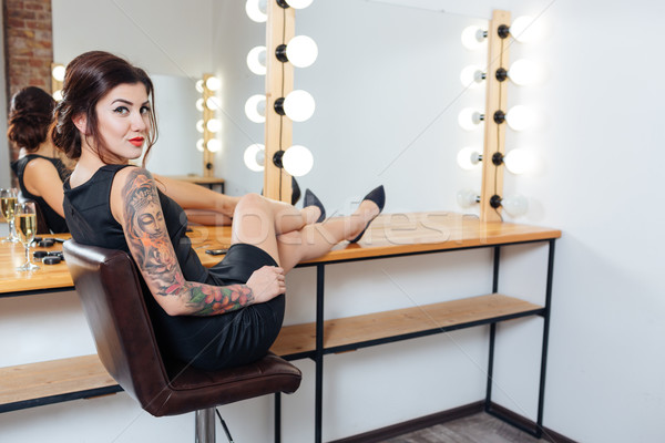 Tattooed woman sitting in dressing room with legs on table Stock photo © deandrobot