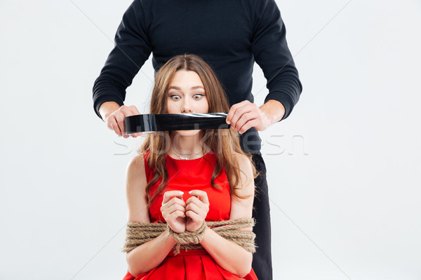 Man covering mouth of woman bounded with ropes by tape Stock photo © deandrobot