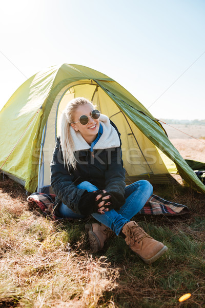 Woman in sunglasses and boots sitting near tent at campsite Stock photo © deandrobot