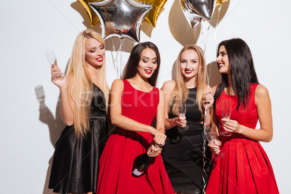 Cuatro sonriendo mujeres apertura botella champán Foto stock © deandrobot