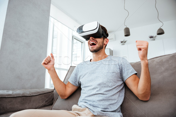 Young man wearing virtual reality device and making winner gesture Stock photo © deandrobot