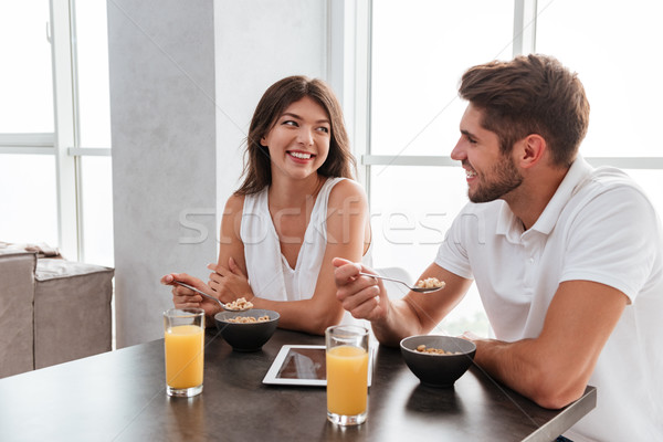 Stock photo: Couple with tablet drinking juice and eating cereals for breakfast