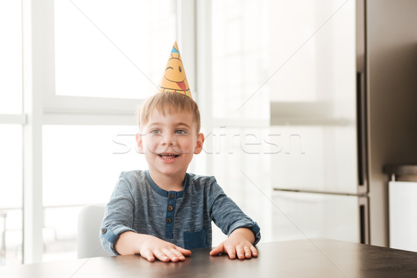 Little happy birthday boy sitting in kitchen while smiling Stock photo © deandrobot