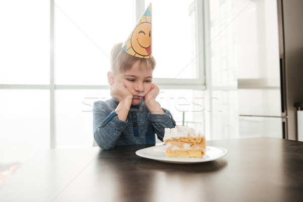 Sad birthday boy sitting in kitchen near cake alone Stock photo © deandrobot