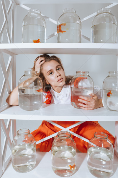 Pretty young woman looking through the closet with gold fishes Stock photo © deandrobot