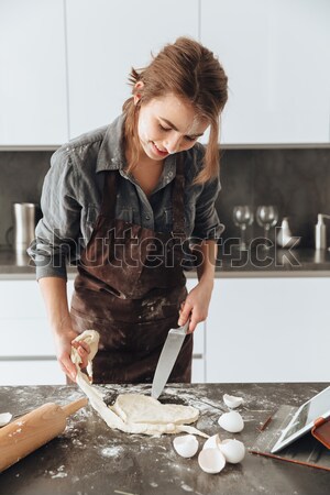 Happy lady standing in kitchen while cooking the dough Stock photo © deandrobot