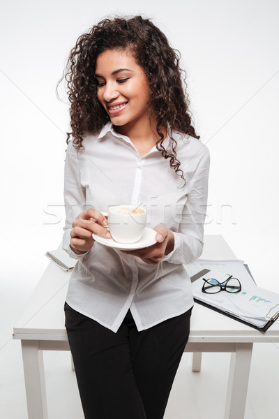 Cheerful african business woman wearing glasses drinking coffee Stock photo © deandrobot