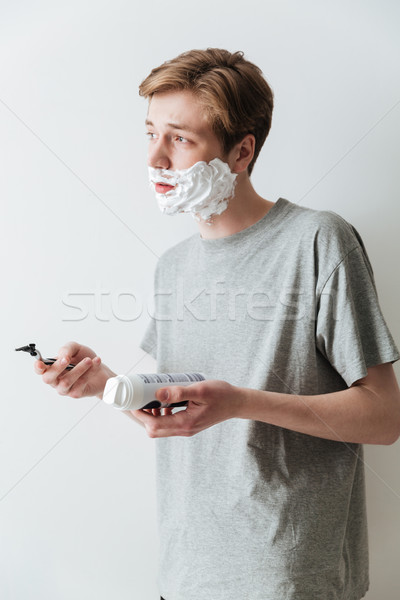 Vertical image of Young Incomprehensible man in shaving foam Stock photo © deandrobot