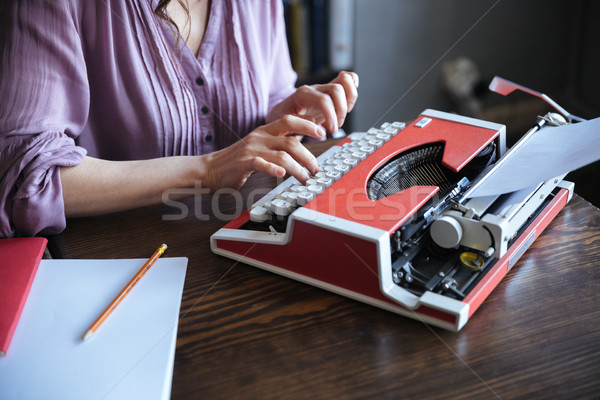 Authoress sitting at the table and typing on typerwriter indoors Stock photo © deandrobot