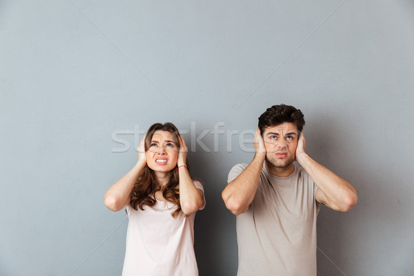 Portrait of an irritated couple covering ears Stock photo © deandrobot