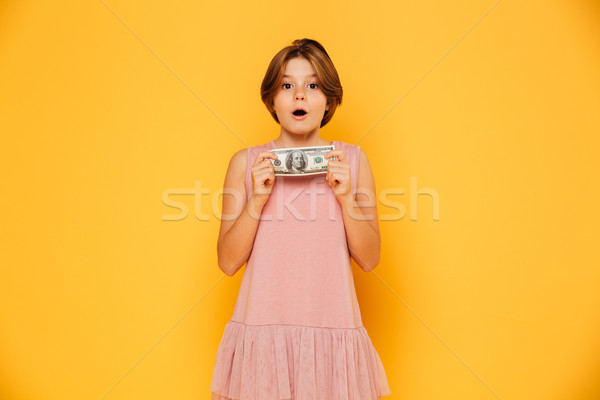 Pretty surprised girl holding dollar and looking camera isolated Stock photo © deandrobot