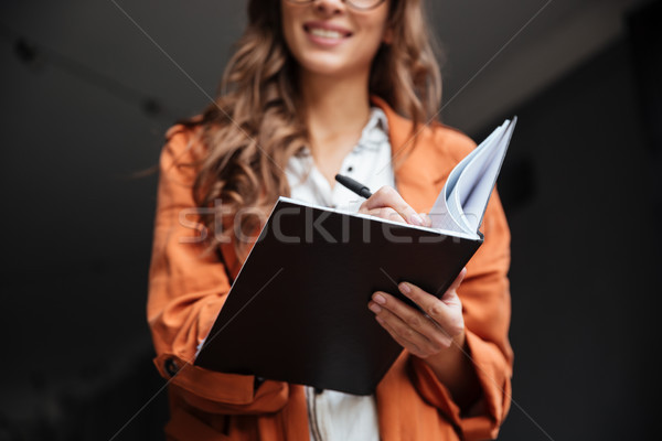 Close up portrait of a smiling woman making notes Stock photo © deandrobot