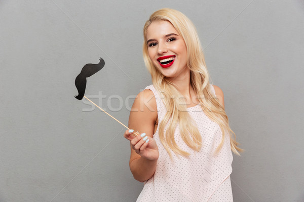 Portrait of a joyful girl holding paper moustache on stick Stock photo © deandrobot