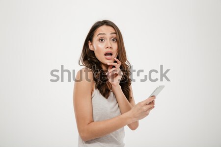 Side view of Shocked brunette woman holding smartphone Stock photo © deandrobot
