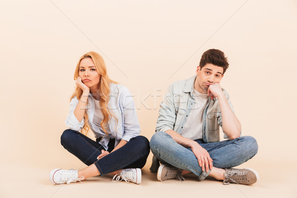 Image of dissatisfied man and woman sitting on the floor with le Stock photo © deandrobot