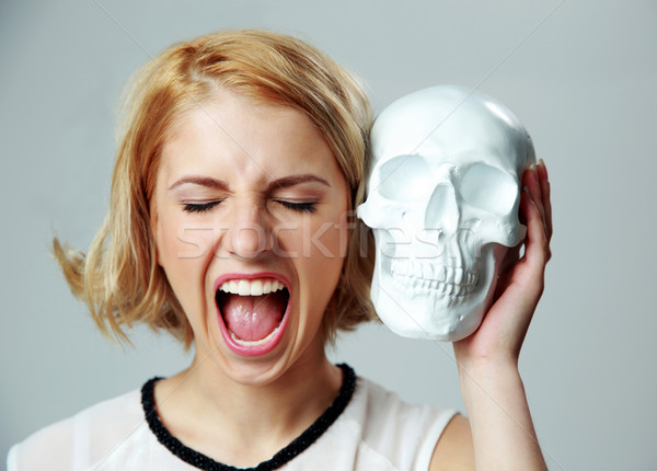 Fiatal nő kiált tart koponya szürke lány Stock fotó © deandrobot