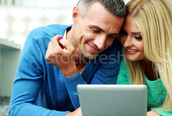Stock photo: Young couple lying on the carpet and using tablet computer together