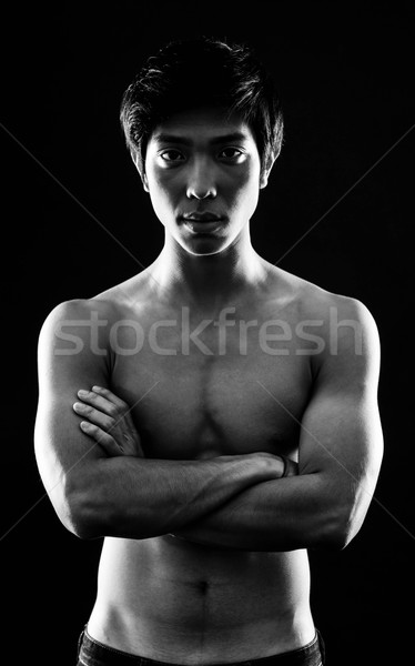 Portrait of a serious asian man with arms folded on black background Stock photo © deandrobot