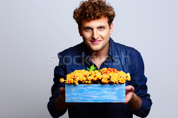 Stock photo: Man holding flowers over blue background